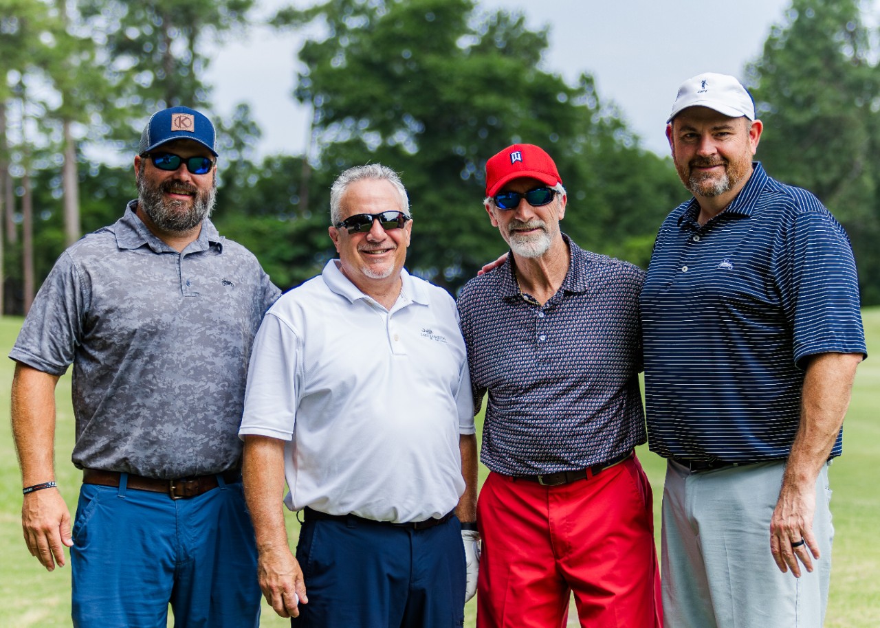 Four men in golf attire pose at a community event hosted by Southern Nuclear, reinforcing bonds within the broader nuclear community.