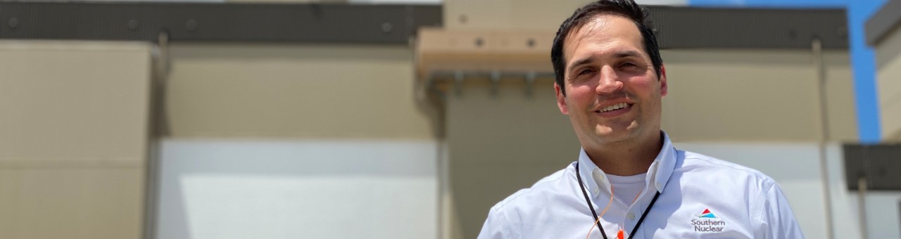 Man in business-casual attire smiles at Southern Nuclear facility, representing nuclear power plant careers in a professional setting.
