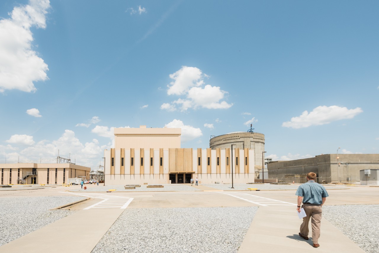 A man walking toward entrance of Joseph M. Farley Nuclear Plant under a bright blue sky, one of Alabama's major nuclear power facilities.
