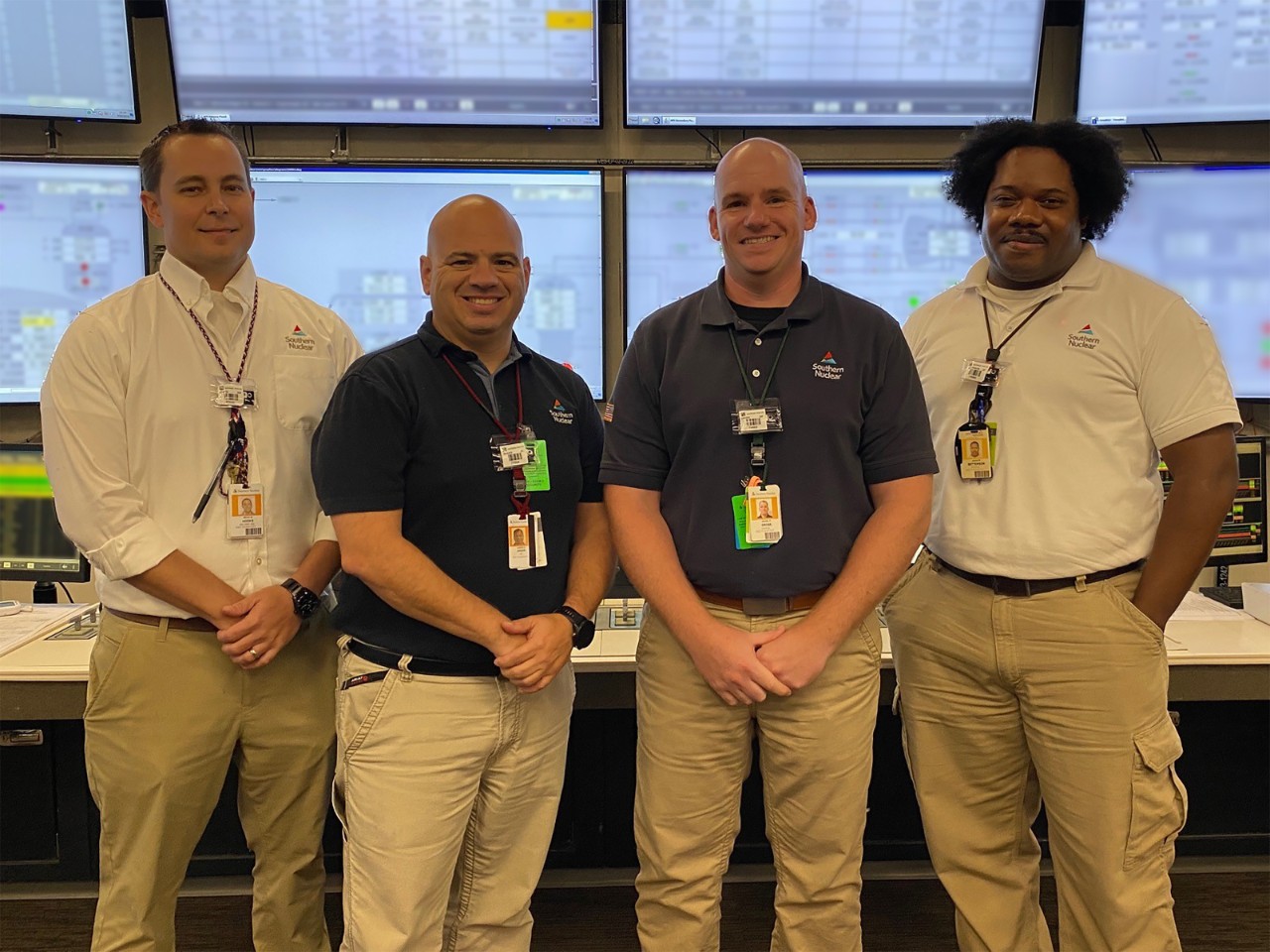 Four Plant Hatch staff members stand smiling in a control room, representing the team at this Georgia nuclear plant.