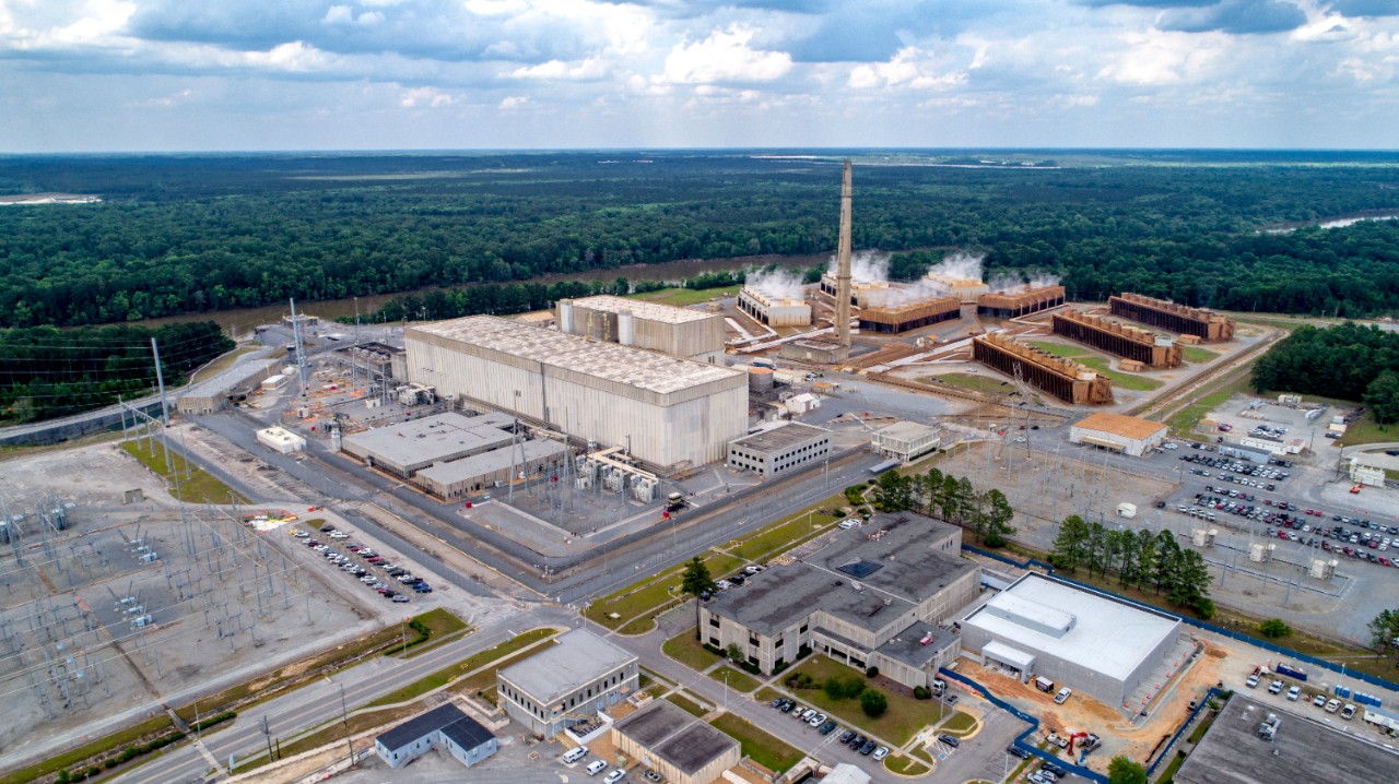 Wide aerial of Plant Hatch in Georgia, with steam billowing from towers and surrounding forest and riverbank clearly visible.